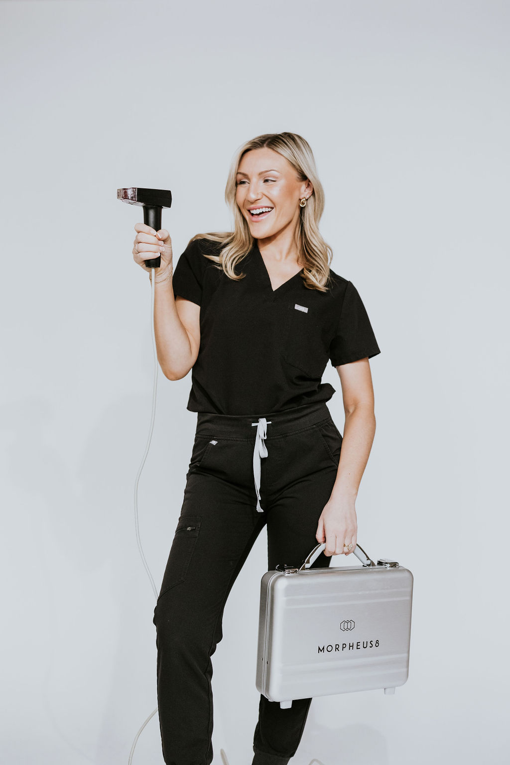 Aesthetician at Hue Aesthetics in Louisville, Kentucky, posing with the Morpheus8 radiofrequency microneedling device, emphasizing expert care and advanced skin rejuvenation.