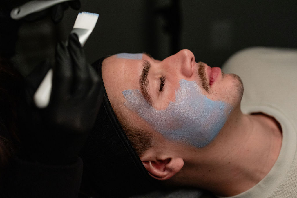 Professional Men’s Facial Treatment Aesthetician performing a customized facial treatment for a male client.